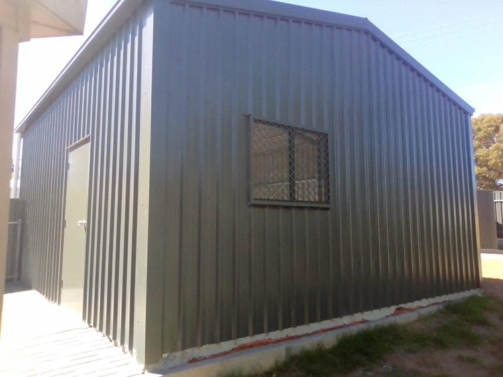 Charcoal domestic backyard shed with roller door and PA door by Trevarth Garages